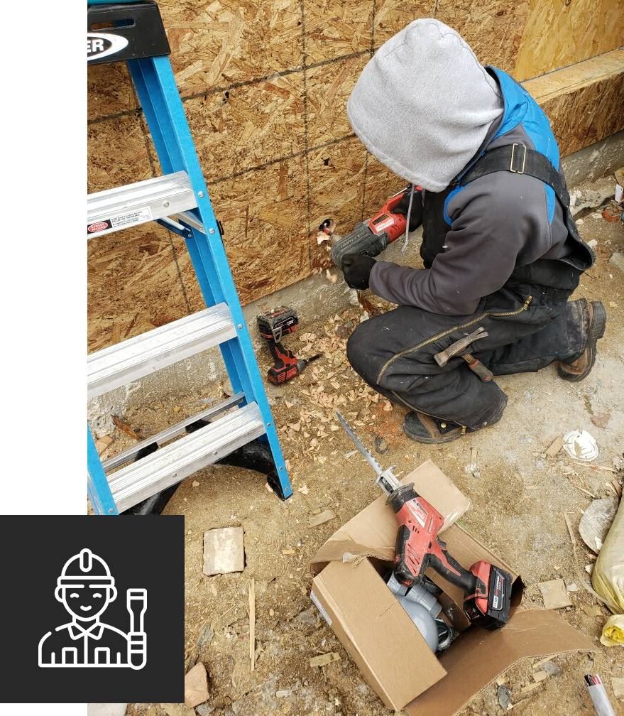 Close up of construction worker's hand drilling holes in wall at construction site.